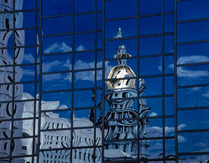 Photograph of a glass building with another building reflected in it.